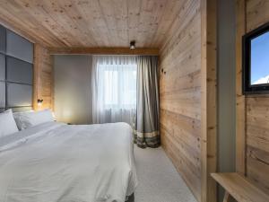 a bedroom with a white bed and a television at Appartement spacieux, cosy avec cheminée, proche pistes et école de ski, idéal pour familles - FR-1-567-12 in Val dʼIsère