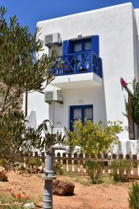 a white house with blue windows and a fence at Aegean Star Hotel in Karavostasi