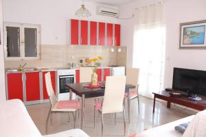 een keuken met rode kasten en een tafel en stoelen bij Apartments Iris in Herceg-Novi