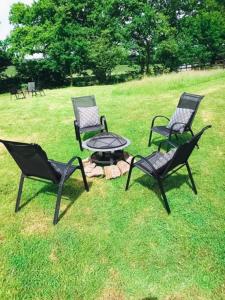 a group of four chairs and a table in the grass at Route 47 Glamping Bell Tents in Cross Hands