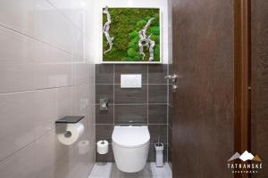 a bathroom with a toilet with a picture on the wall at Luxusný Apartmán Hrebienok Resort - Tatranské Apartmány in Vysoke Tatry - Stary Smokovec