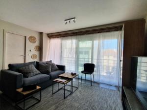 uma sala de estar com um sofá e uma janela grande em stevans place em Bredene
