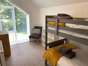 a bedroom with a bunk bed and a chair at Snowdon Holiday Let, brand new home in the heart of Llanberis in Llanberis
