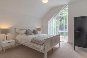 a white bedroom with a bed and a large window at Snowdon Holiday Let, brand new home in the heart of Llanberis in Llanberis