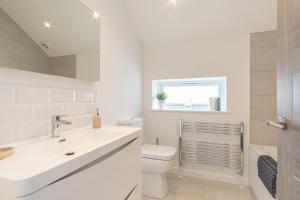 a white bathroom with a sink and a toilet at Snowdon Holiday Let, brand new home in the heart of Llanberis in Llanberis
