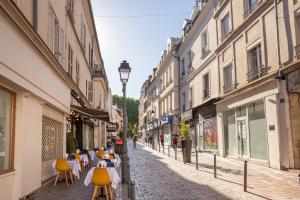 an alley with tables and chairs on a street with buildings at Charme de l'ancien aux portes de Paris ! in Charenton-le-Pont