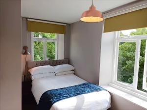 a bedroom with a bed and two windows at Spring Grove B&B in Huddersfield