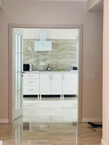 a kitchen with white cabinets and a glass door at M House Băile Herculane in Băile Herculane