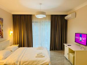 a hotel room with a bed and a flat screen tv at M House Băile Herculane in Băile Herculane