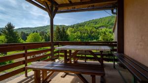 a picnic table on a balcony with a view of the mountains at Apartman Rozmari in Lokve
