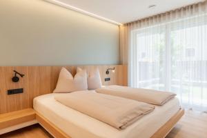 a bedroom with a bed with a large window at VANEA - Alp Relax Guesthouse in Chienes