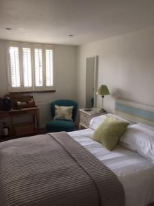 a bedroom with a large bed and a chair at Stone Cottage in Thornage +28 photos