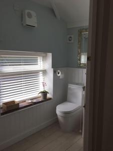 a bathroom with a white toilet and a window at Stone Cottage in Thornage +30 photos