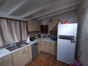 a kitchen with a white refrigerator and a sink at Stonemakers Hide in Corfu