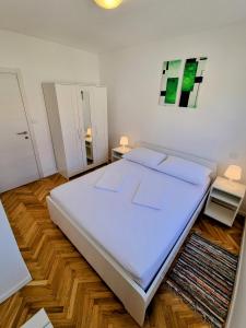 een slaapkamer met een groot wit bed en een spiegel bij Omiš City Apartment in Omiš