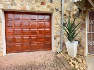 a wooden garage door with a potted plant in front of a house at Het Kadootje - Southbroom's little gift - 6 sleeper 3 bedroom apartment in Southbroom