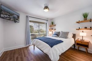 a white bedroom with a bed and a window at Shore Nuff in Jacksonville Beach