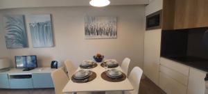 une table à manger blanche avec des chaises et une télévision dans l'établissement Apartamento S. João, à Alvor
