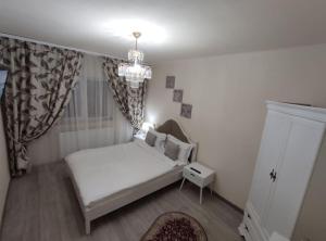 a small bedroom with a white bed and a chandelier at RELAX Downtown Suite in Constanţa