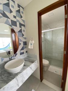 une salle de bain avec un lavabo, des toilettes et un miroir dans l'établissement Santo Mar São Miguel do Gostoso, à São Miguel do Gostoso