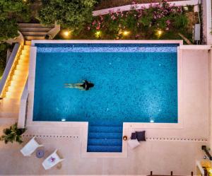 a man swimming in a swimming pool at night at Villa Ragusea With a Private Beach in Slano