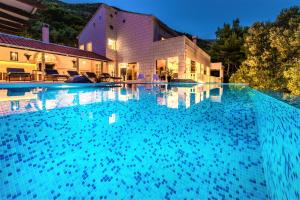 a large swimming pool in front of a house at Villa Ragusea With a Private Beach in Slano