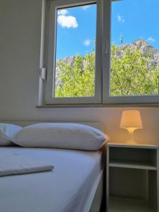 een slaapkamer met een raam en een bed en een lamp bij Omiš City Apartment in Omiš