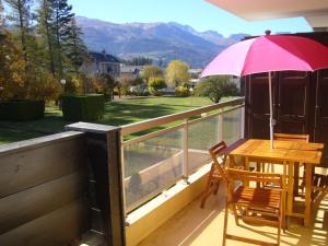 a table and chairs on a deck with an umbrella at Appartement T2 calme avec belle terrasse à Barcelonnette - FR-1-165A-99 in Barcelonnette