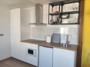 a small kitchen with white cabinets and a sink at A Casiña do Camiño in Baamonde