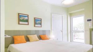 een slaapkamer met een groot wit bed met oranje kussens bij Mandarinoarancio in Alezio