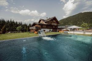 - une piscine en face d'une maison en rondins dans l'établissement Hoagascht, à Flachau