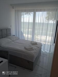 um quarto com uma cama e uma grande janela em Apartament z widokiem na morze w kompleksie Hevenia em Rewal