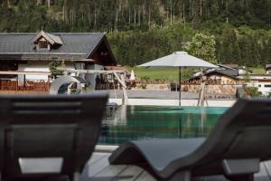 a swimming pool with a house and an umbrella at Hoagascht in Flachau
