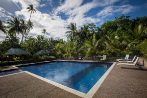 a swimming pool with chairs and palm trees at Tawali Leisure & Dive Resort in Alotau