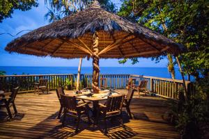 einen Tisch mit Stühlen und einen großen Sonnenschirm auf einer Terrasse in der Unterkunft Tawali Leisure & Dive Resort in Alotau