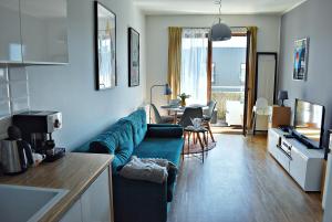 a living room with a blue couch and a table at Sopotinn Apartment in Sopot