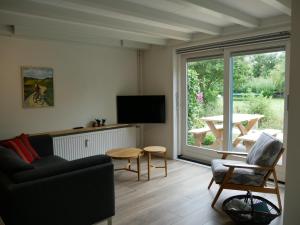 ein Wohnzimmer mit einem Sofa und einem Tisch in der Unterkunft Jonas - Luxe appartement naast de duinen in Oosterend