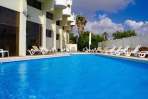 a large blue swimming pool with chairs and a building at Sea front panoramic duplex roof-top in Herzliya