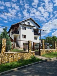 una casa blanca con una valla de piedra en Vila San Nicoara en Curtea de Argeş