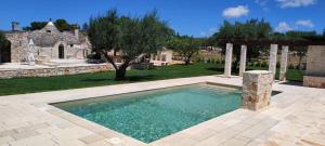 a swimming pool in a yard with a stone building at Villa "Il Trullo di Filomena" in Castellana Grotte