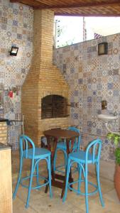 uma mesa e duas cadeiras azuis e uma lareira de tijolos em Casa perto da praia com piscina, churrasqueira em SLZ em São Luís