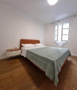 a white bedroom with a bed and a window at Old town Apartments in Herceg-Novi