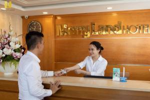 a man and a woman shaking hands at a counter at Merry Land Hotel Da Nang in Danang