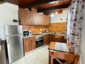 eine Küche mit Holzschränken und einem Kühlschrank aus Edelstahl in der Unterkunft Sun, Relax & Lava, Free wifi 600mb, BBQ in Tinajo