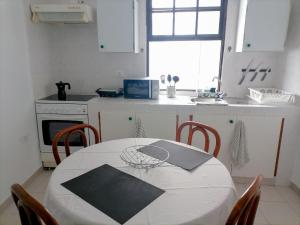 eine Küche mit einem weißen Tisch, einem Tisch und Stühlen in der Unterkunft Low Island House in Los Silos