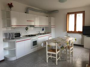 a kitchen with white cabinets and a table with chairs at Giò Appartamenti Vacanze in Aymavilles