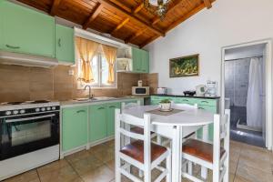a kitchen with green cabinets and a white table at Skopelos Amigdalia cottage in Skopelos Town