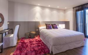 Hotel Boutique Abadia del Maestrat في Sarratella: غرفة نوم بسرير ابيض كبير وسجادة حمراء