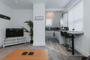 a kitchen and a living room with a table and a tv at 1 Bed Stylish City Flat 2nd Floor close to City Centre with free parking, king size bed & Wi-Fi in Nottingham