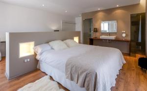 a bedroom with a large white bed and a bathroom at Hotel Boutique Abadia del Maestrat in Sarratella